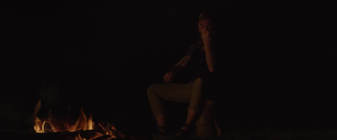 A man plays violin in front of a fire