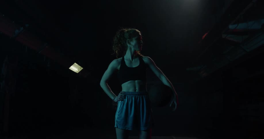 A woman stands in a gym holding a basketball