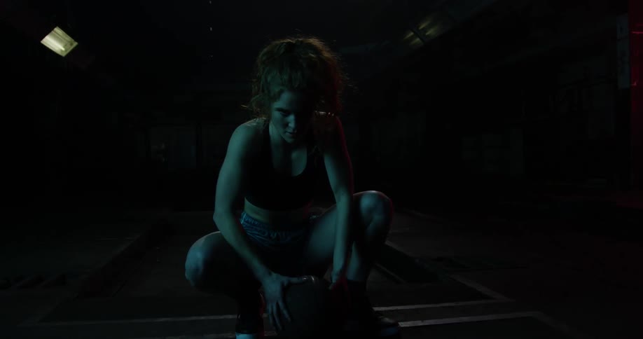 A woman is leaning down gripping a basketball