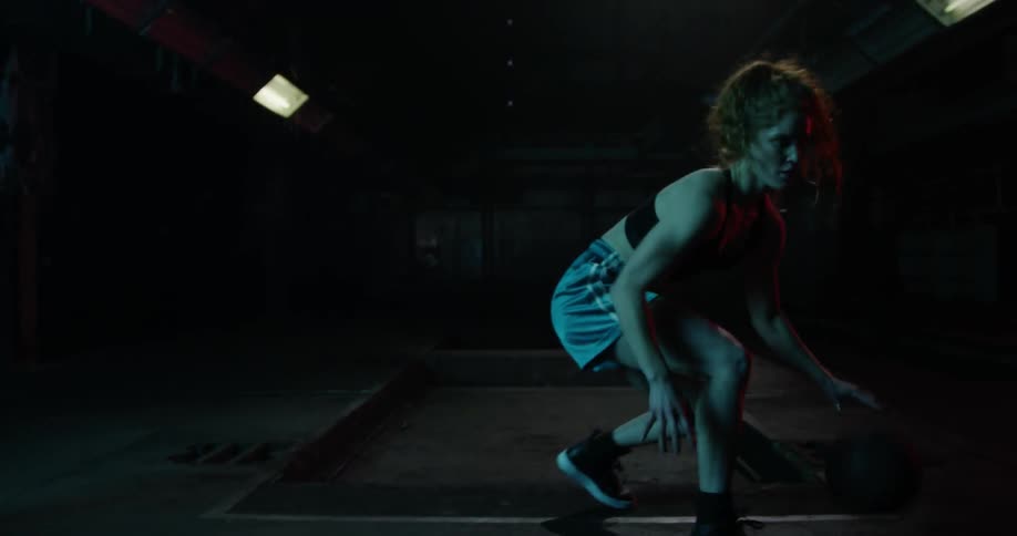 Woman dribbling basketball on court at night