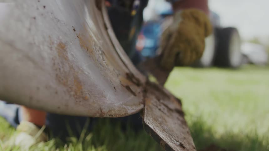 Person scrapes dirt from a metal object