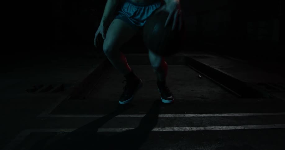 A woman dribbles a basketball between her legs