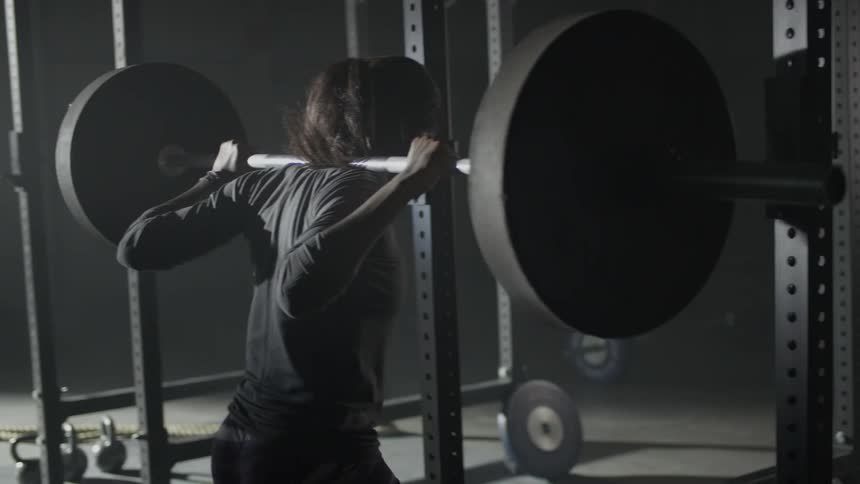 A woman is squat pressing weights