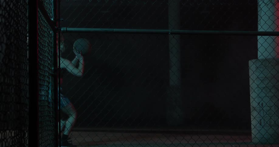 A woman shoots the basketball in the dark gym