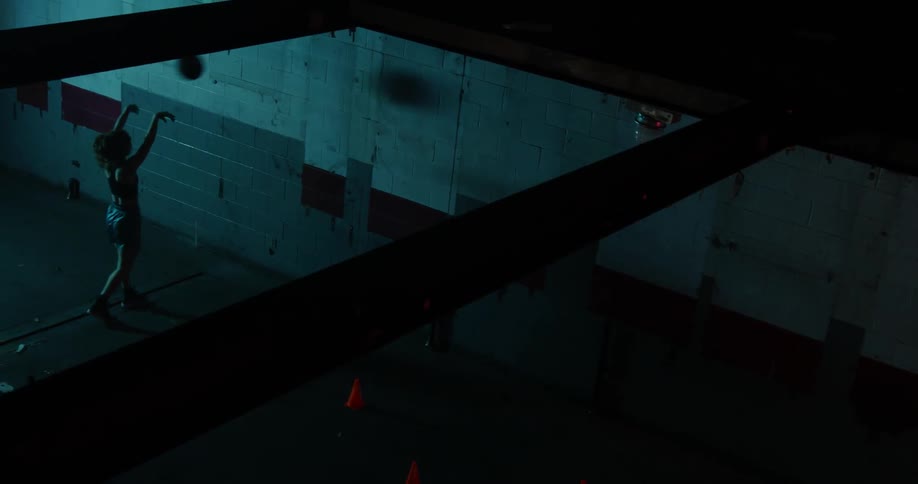 A woman bounces a basketball off the wall