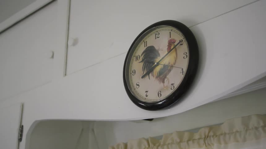 A clock with a rooster on it is mounted on the wall