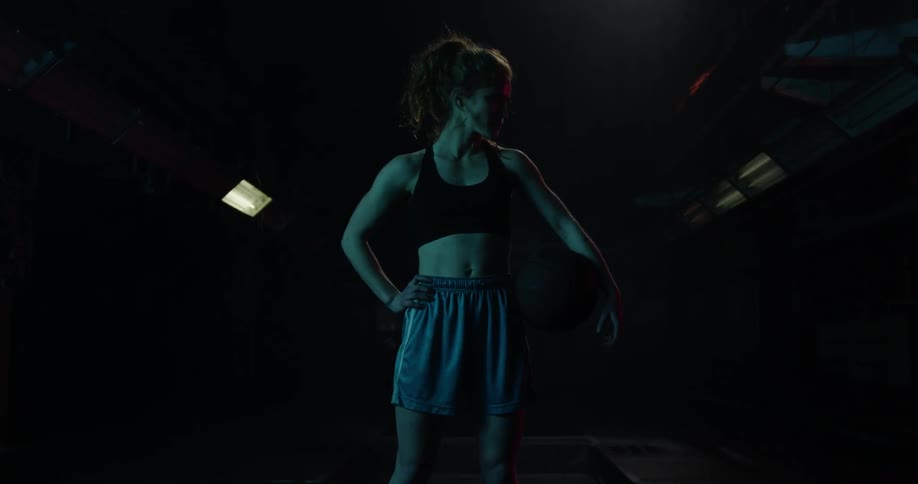 A woman stands in a gym holding a basketball