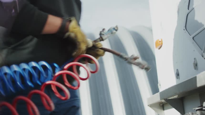 A worker is attaching cables to a generator during the day