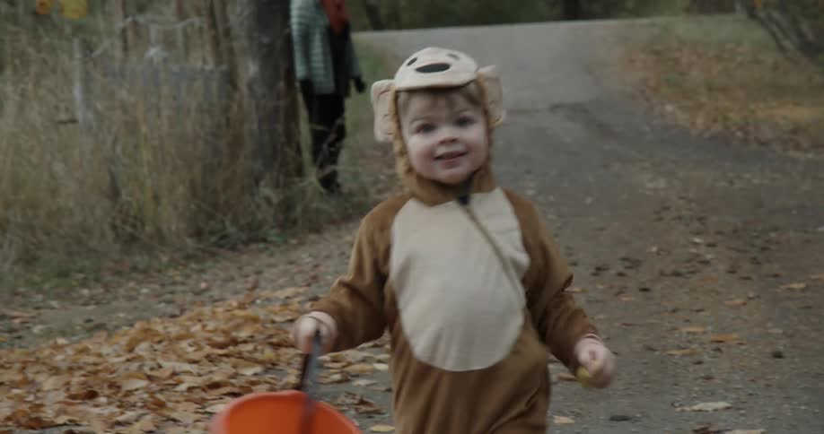 A toddler boy wearing a halloween costume is running