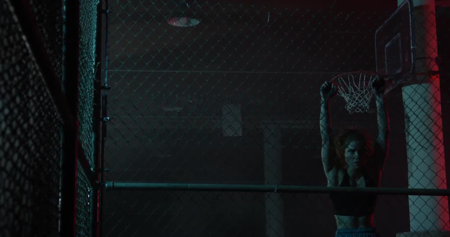 A woman stretches on an indoor fence