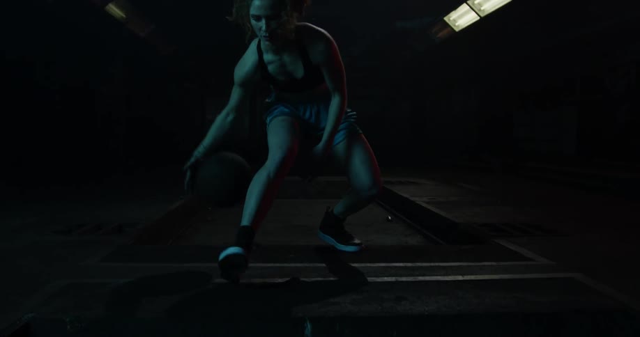 A woman dribbles a basketball between her legs