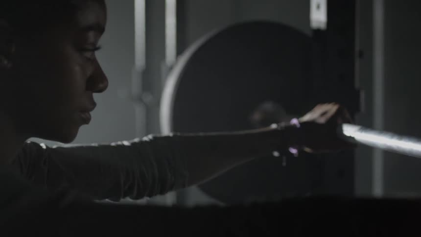 Woman holds onto a barbell with both hands