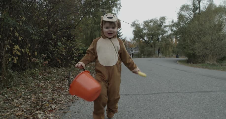 A child in a halloween costume is jumping as he walks