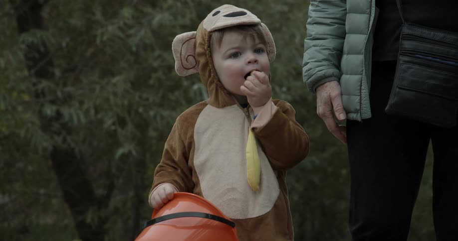 A woman walks a young child to trick or treat