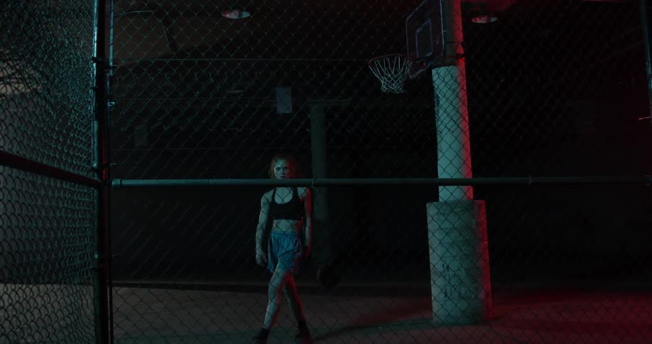 A woman throws a basketball against a fence