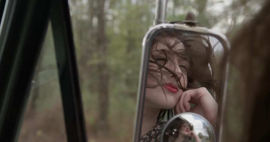 A woman leans out the window with her hair blowing smiling