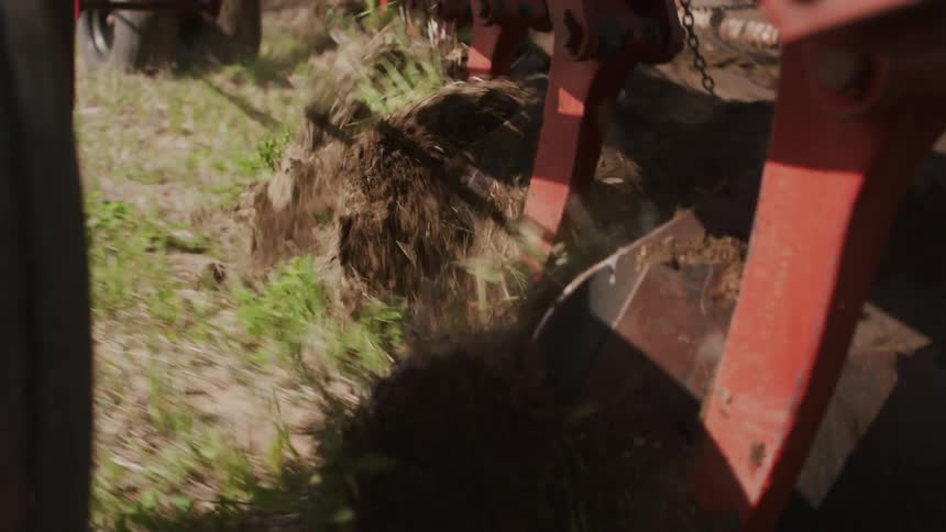 A tractor drives across a field turning the soil