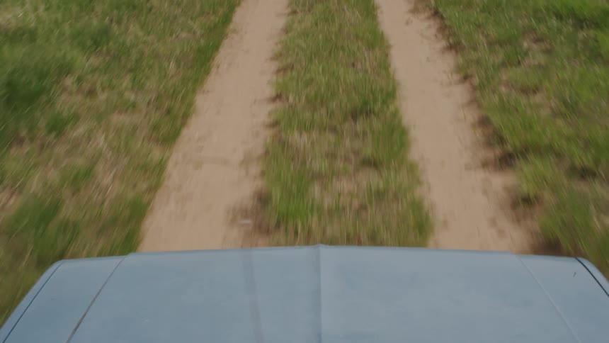 A car drives along dirt tracks in grass