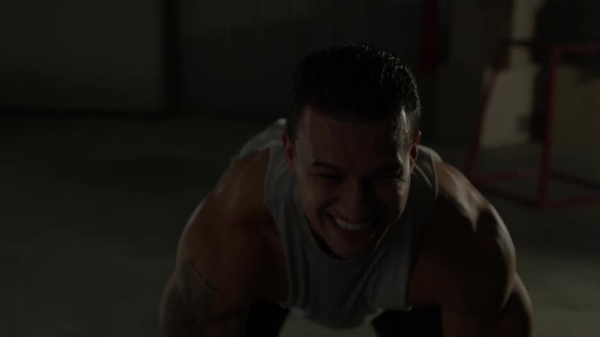 A man grimaces as he lifts weights