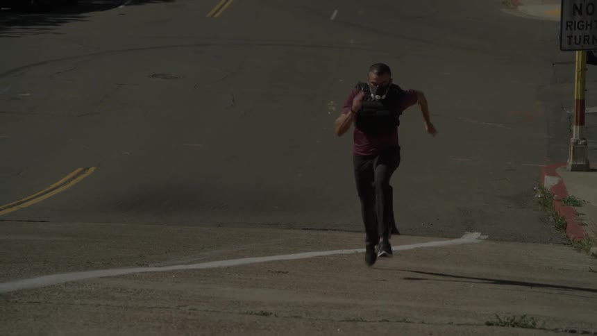 A man runs frantically up a street