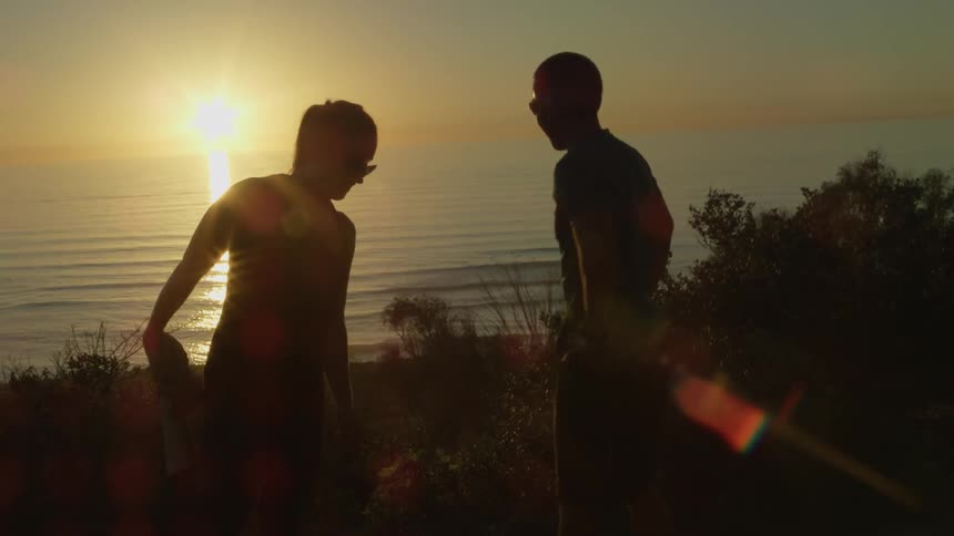 A man and woman stretch by the ocean