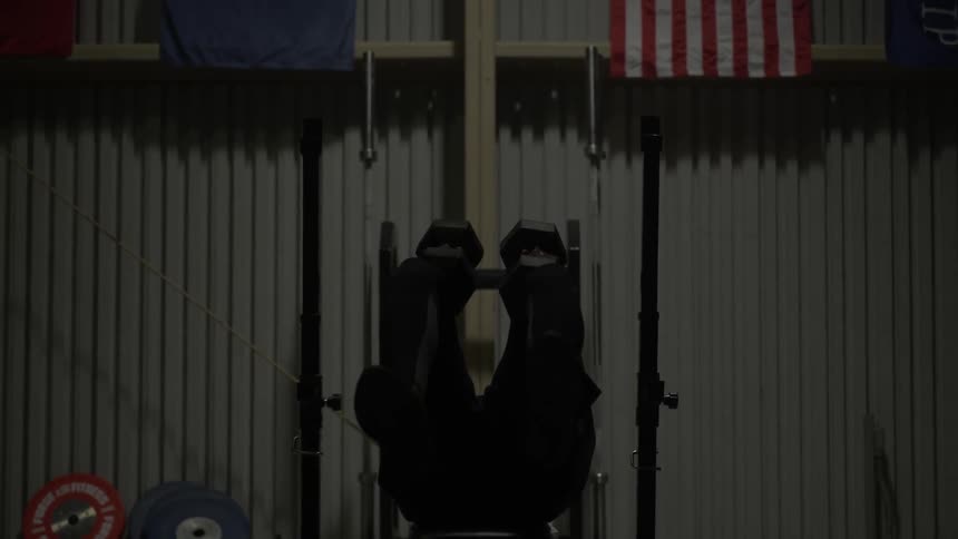 A man lifts weights and sits up on a bench
