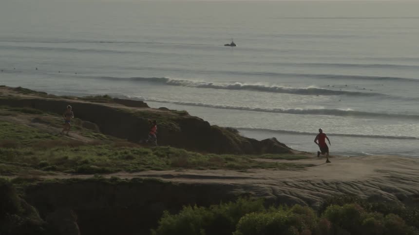 Three people run along a dirt trail
