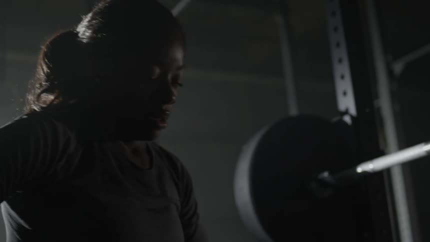 A woman looks tired after lifting weights