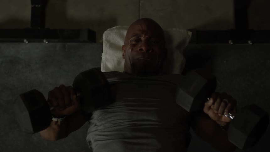 A man works out using dumbbells at a gym
