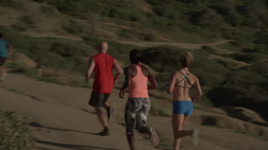 A group of people run along a dirt trail