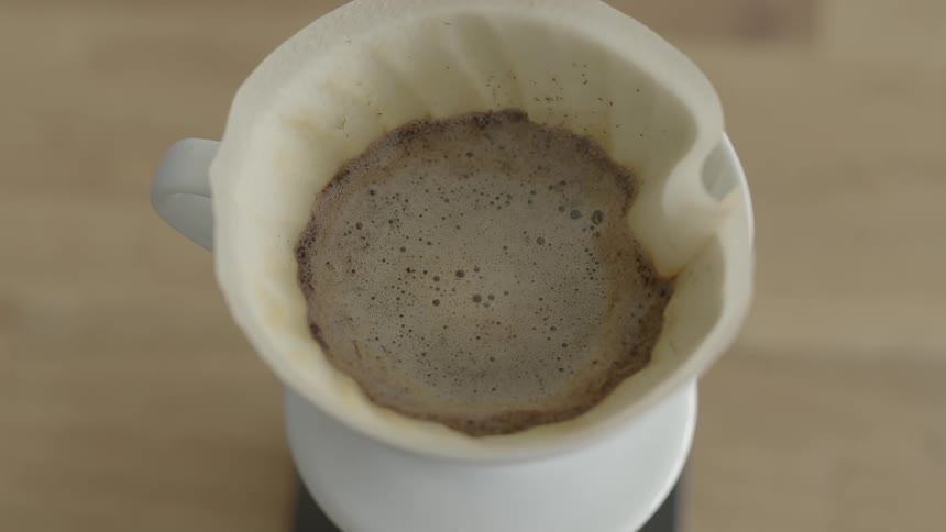 A cup of a steaming hot beverage sits on a table