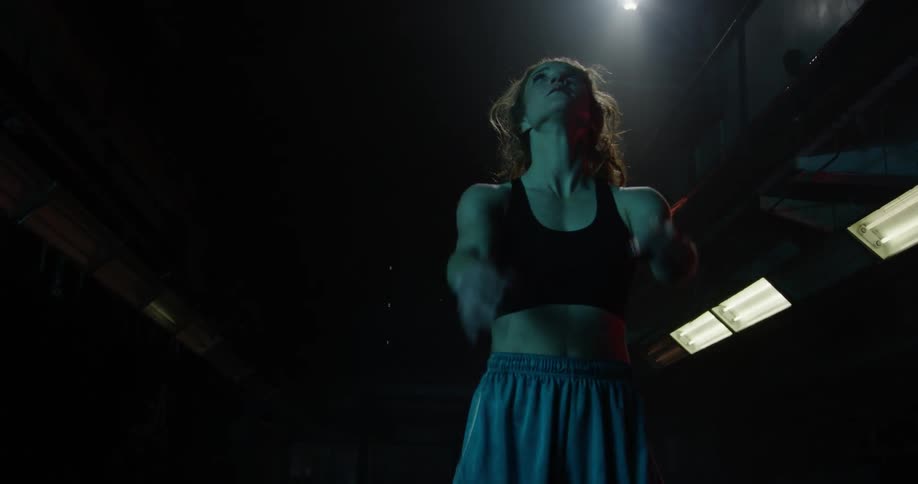 Woman in a sports bra bounces a basketball and then catches it with both hands
