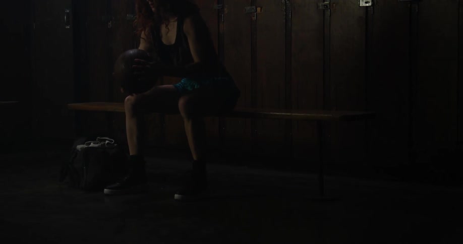 A woman packs her gym bag in a locker room