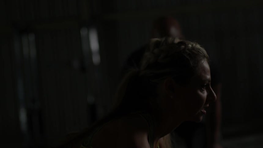 A woman is lifting weights as a coach watches on