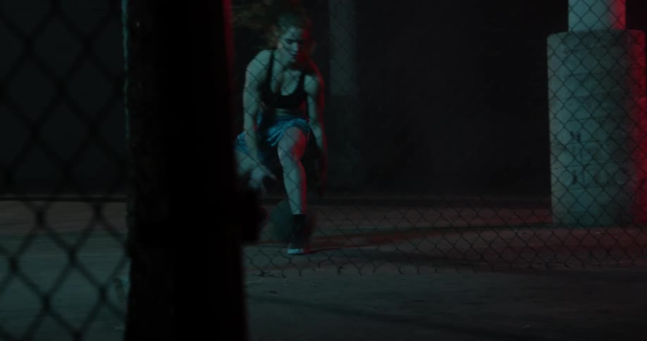 A woman is dribbling a basketball between her legs