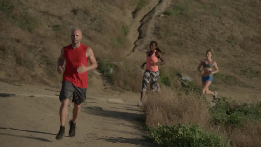 Joggers run up a hill on a sunny day
