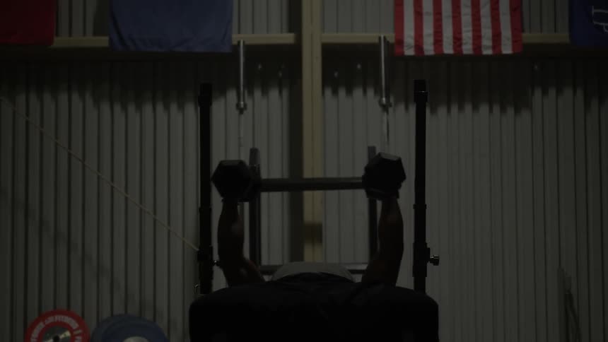 A man is lifting dumbbells over his head