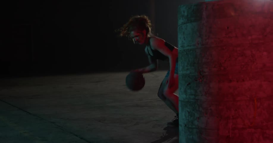 A woman dribbles a basketball between her legs