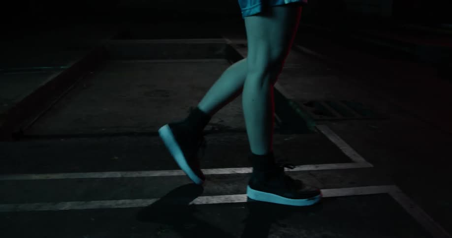 A woman walks in a dimly lit gym