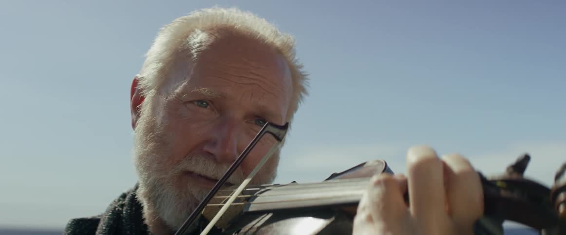 A man with white hair is playing the violin