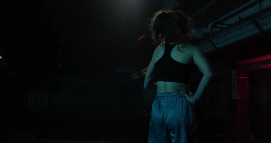 A woman stands in a dark gymnasium