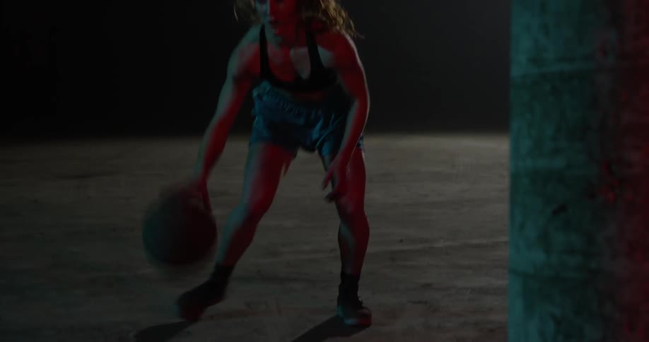 A woman bounces a basketball and shoots