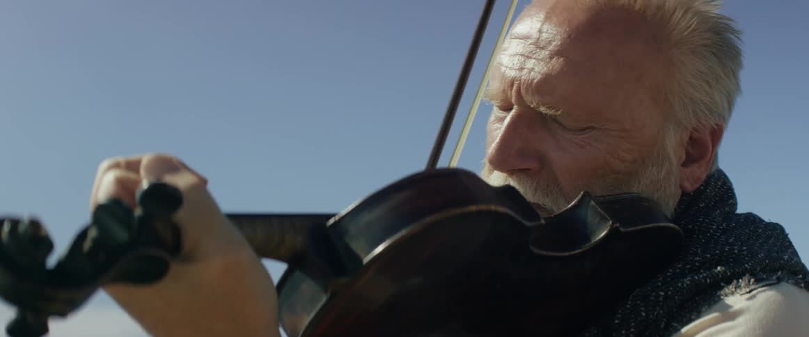 A man is playing the violin on a bright sunny day