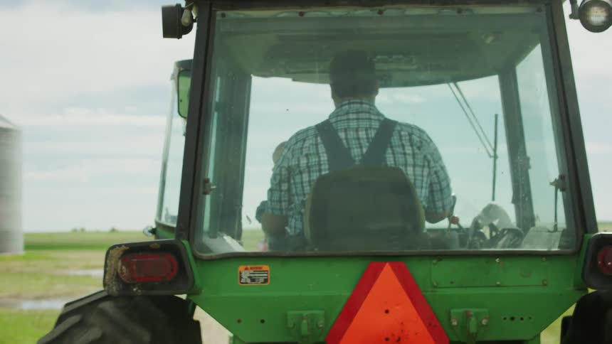 A farmer drives a tractor in a rural field