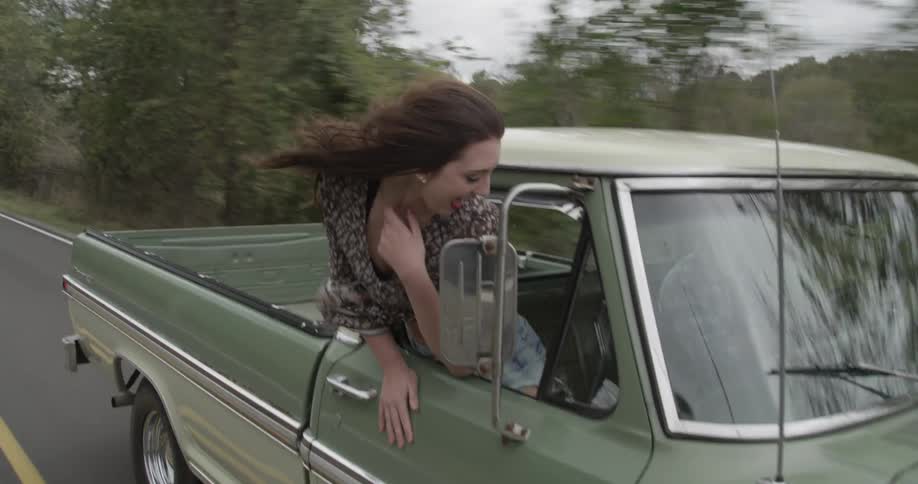 Woman hangs halfway out of a moving truck
