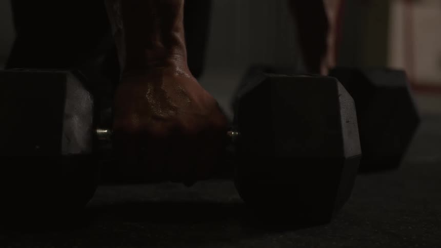 A man picks up two dumbbells from the floor