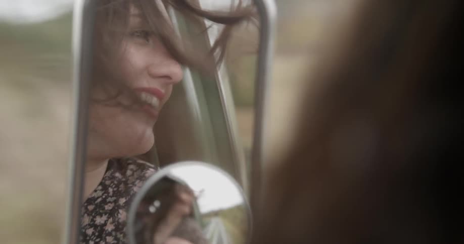 A woman looks out the window of the car smiling
