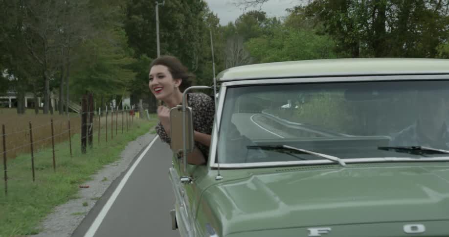 A woman is sticking her head out of the window of a moving truck