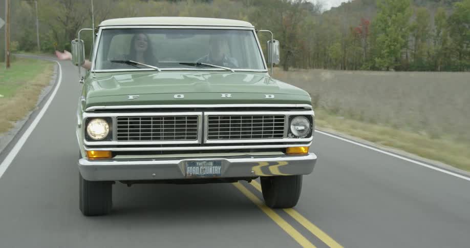 Pick up truck travels down the road as a woman inside waves her arm outside the window