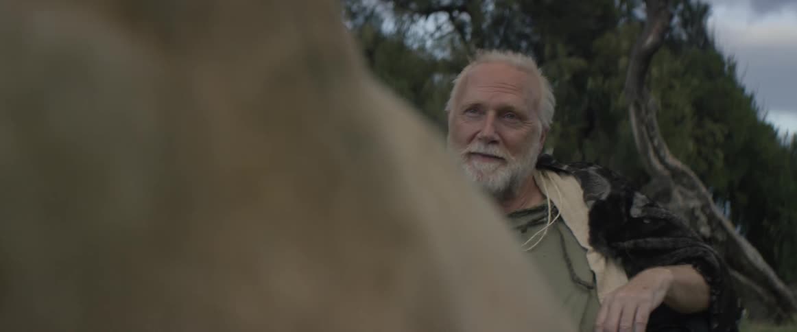 An old man is sitting at a table looking at a younger man